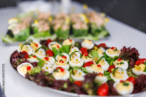 Colorful appetizer platters featuring deviled eggs decorated with daisy edible flowers and fresh vegetables © encierro