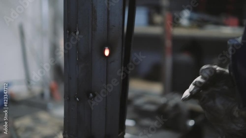 Closeup of blacksmith wearing helmet and gloves welding a piece of metal with tig in the workshop photo