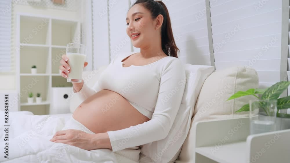 Asian pregnant woman drinking milk or soybean milk before go to bed in bedroom at home. Asian mother health care and nourish womb while pregnancy. Asian pregnant woman drinking milk or soybean milk before go to bed in bedroom at home. Asian mother health care and nourish womb while pregnancy.