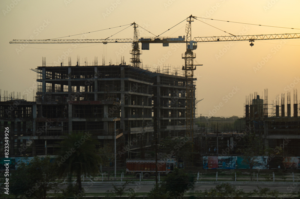 A large building is under construction and has two large cranes. A large building is under construction and has two large cranes.