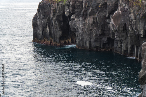 A beautiful coastal area in eastern part of Japan. A clear blue sky and an orange sunrise reflects on the sea water. A big rock formation in the coast line. Island from the distance.
