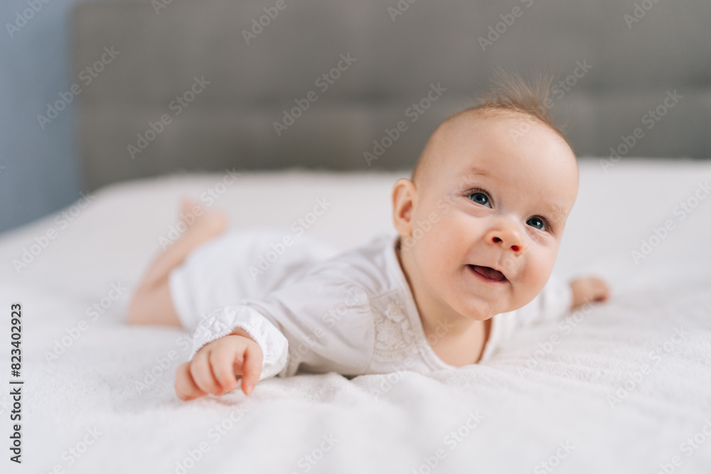 Cute little newborn girl crawling on bed in bedroom. Infant baby resting playing lying down on blanket at home. Rising girl, first steps in crawling after hand plank. Purity, innocence concept. Cute little newborn girl crawling on bed in bedroom. Infant baby resting playing lying down on blanket at home. Rising girl, first steps in crawling after hand plank. Purity, innocence concept.
