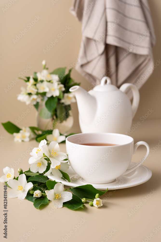A white tea cup and teapot with a jasmine flowers A white tea cup and teapot with a jasmine flowers
