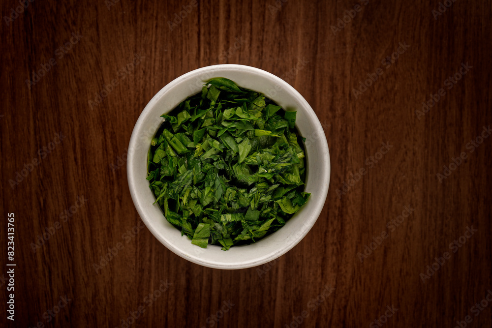 Top view of a bowl full of chopped basil on a wooden table Top view of a bowl full of chopped basil on a wooden table