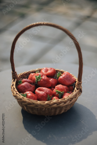 Mature red strawberries on a black table and fresh ripe strawberries in a wooden basket. Red on black