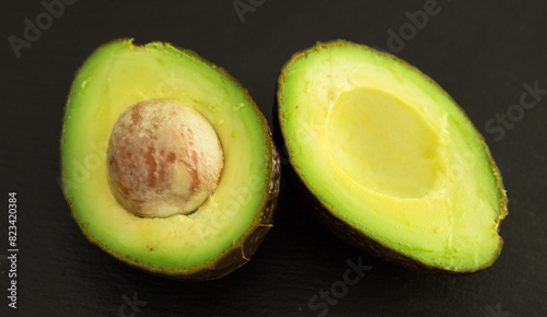 Ripe halved avocado with bone on black stone board