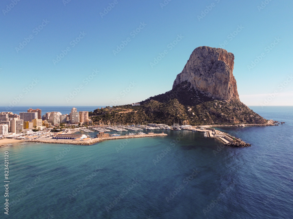 Naklejka premium Scenic rocky beach by the ocean with Spanish architecture: Spain, Calpe