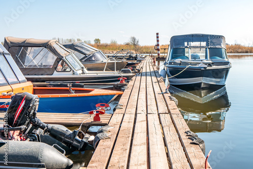 Wallpaper Mural Fishing boats moored at wooden pontoon pier in early morning. Modern motorboats in small docks on calm river. Ships in lake port on spring day Torontodigital.ca