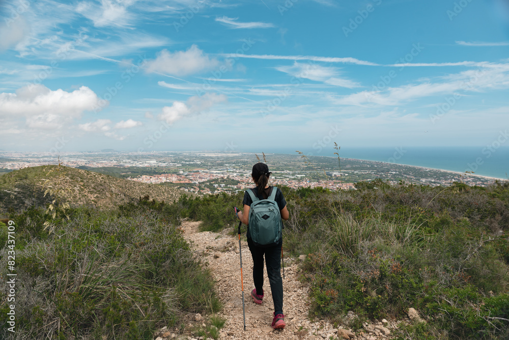 Hiker on a mountain trail back to the city, with a breathtaking view of the Mediterranean coast.