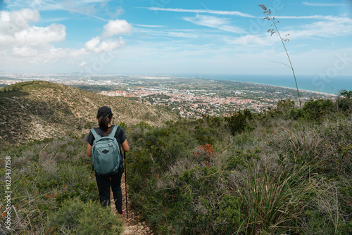 Hiker descending the mountain towards the city, with breathtaking views. © Gusta Cabrera