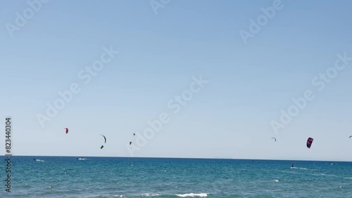 Kite surfers riding the waves in the ocean on a clear day, showcasing an exciting water sport.