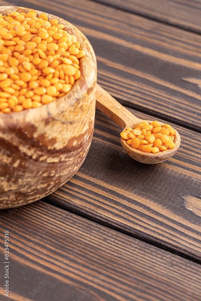 Photo of red lentils in wooden bowl with wooden measuring cup on wooden background. Healthy lifestyle. Vegetarian and vegan diet. Photo of red lentils in wooden bowl with wooden measuring cup on wooden background. Healthy lifestyle. Vegetarian and vegan diet.