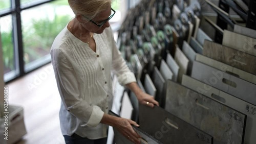 Happy mature woman touching sample flooring for home renovation redecorating project in a design center showroom. photo