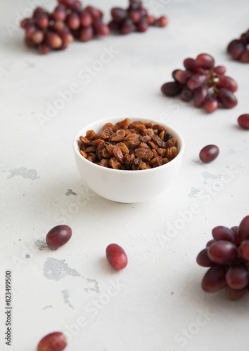Brown dried sweet raisins on light background with red grapes.