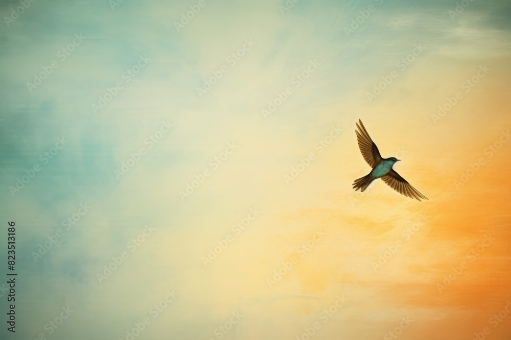 Fototapeta premium A solitary bird soars through a vibrant sky at sunset, with hues of orange and blue blending beautifully in the background.