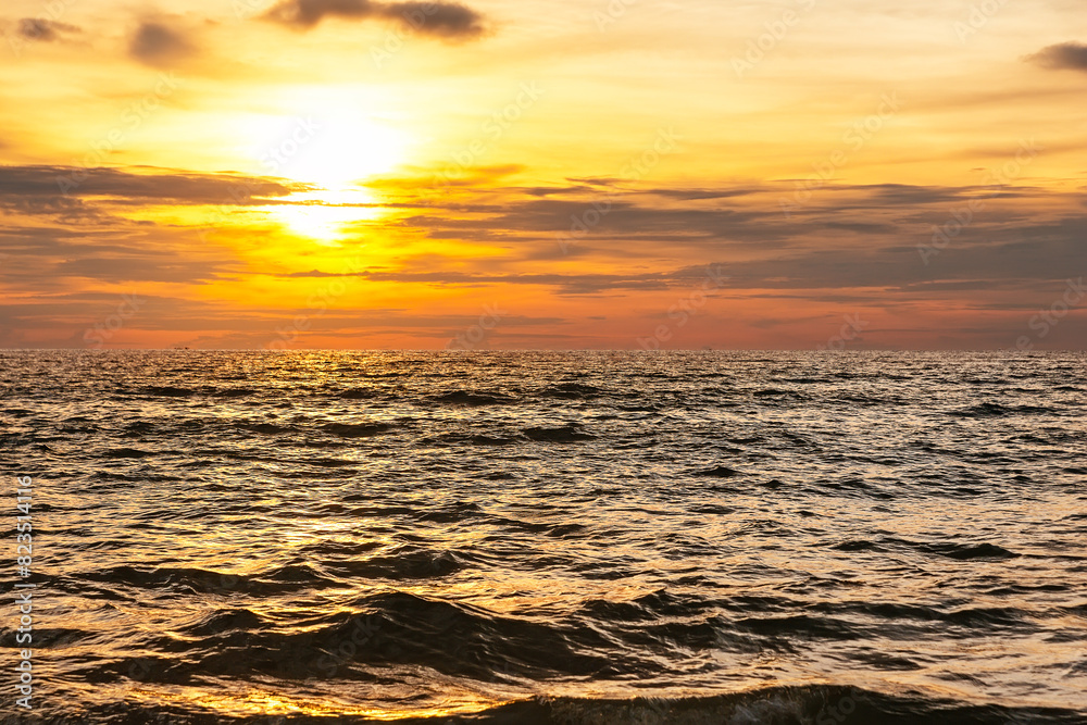 Obraz premium Amazing golden sunset with sea waves against a cloudy sky in Phuket, Thailand.