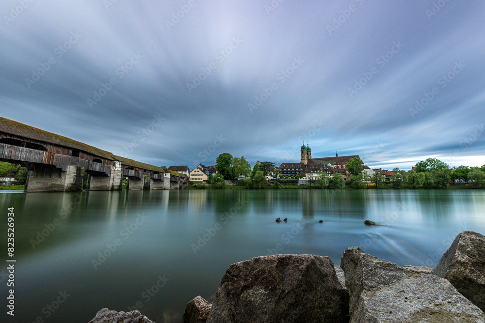 Fototapeta premium skyline of bad säckingen germany with reflection of the ancient wooden bridge and saint fridolin church in the river rhine 