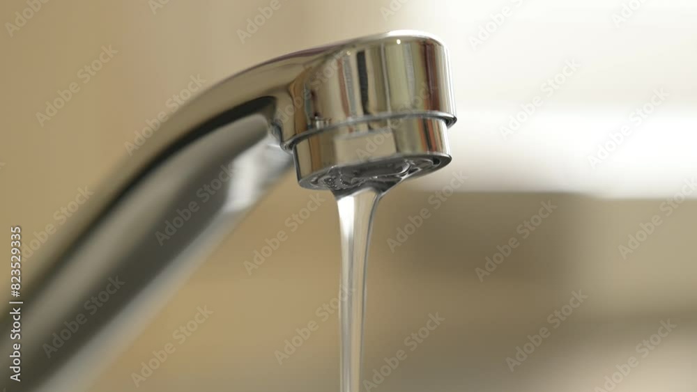 Small trickle of water falling from tap. Water flowing from faucet in kitchen Small trickle of water falling from tap. Water flowing from faucet in kitchen