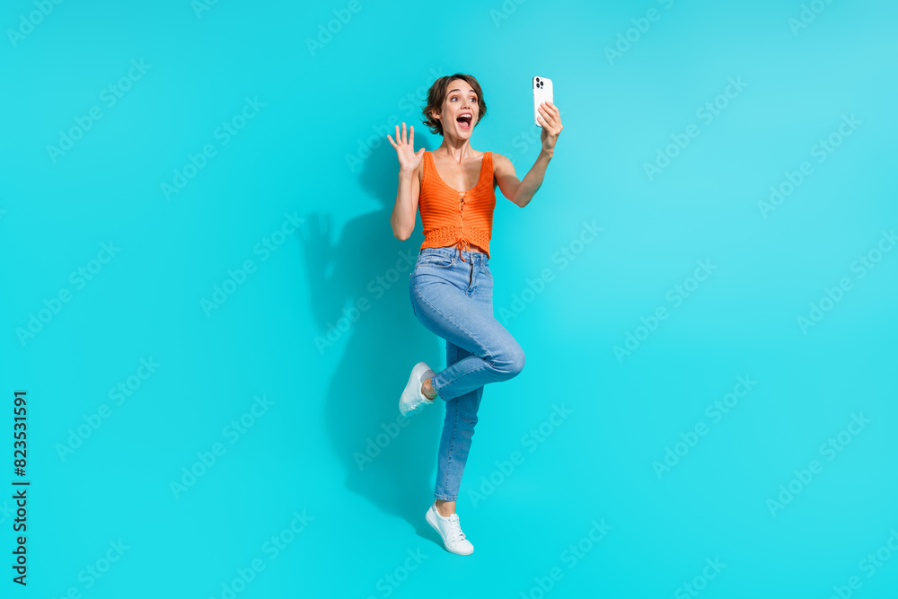 Full size photo of cheerful positive girl dressed knitwear top waving hand make selfie on smartphone isolated on blue color background Full size photo of cheerful positive girl dressed knitwear top waving hand make selfie on smartphone isolated on blue color background