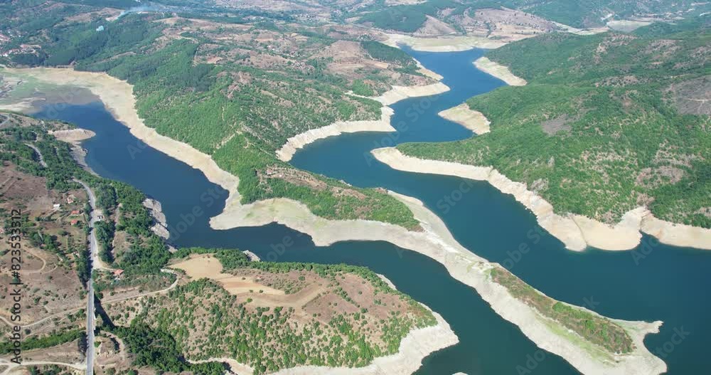 Panoramic aeria view of of turquoise reflecting lake reservoir dam and mountains during drought season when water is used for agriculture irrigation
