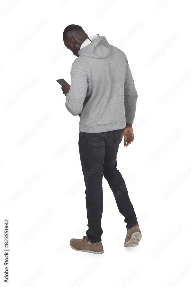 Naklejka premium back,side view of a man walking and looking at smartphone on white background