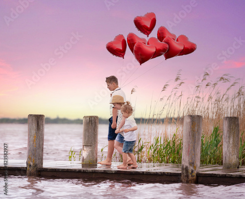 children walking on a wooden jetty with red heart balloons
