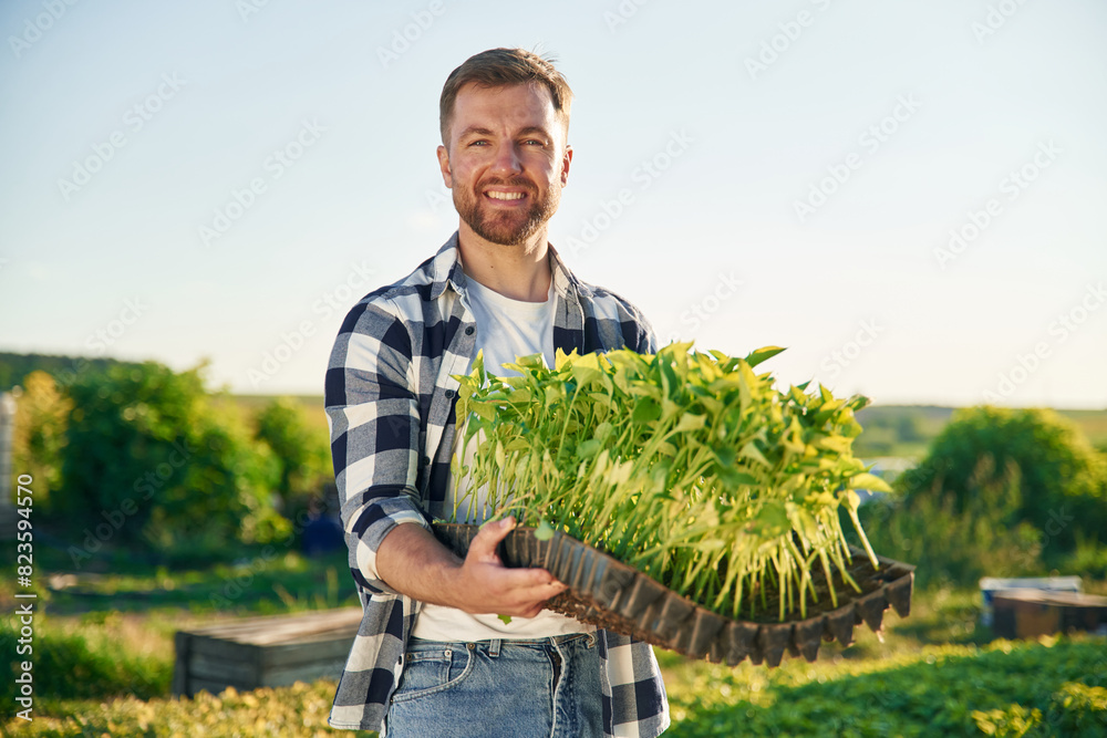 Fototapeta premium Bunch of plants in hands. Adult farmer is outdoors