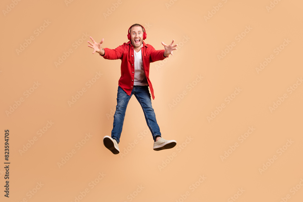 Full size photo of nice young man jump fall empty space wear red shirt isolated on beige color background