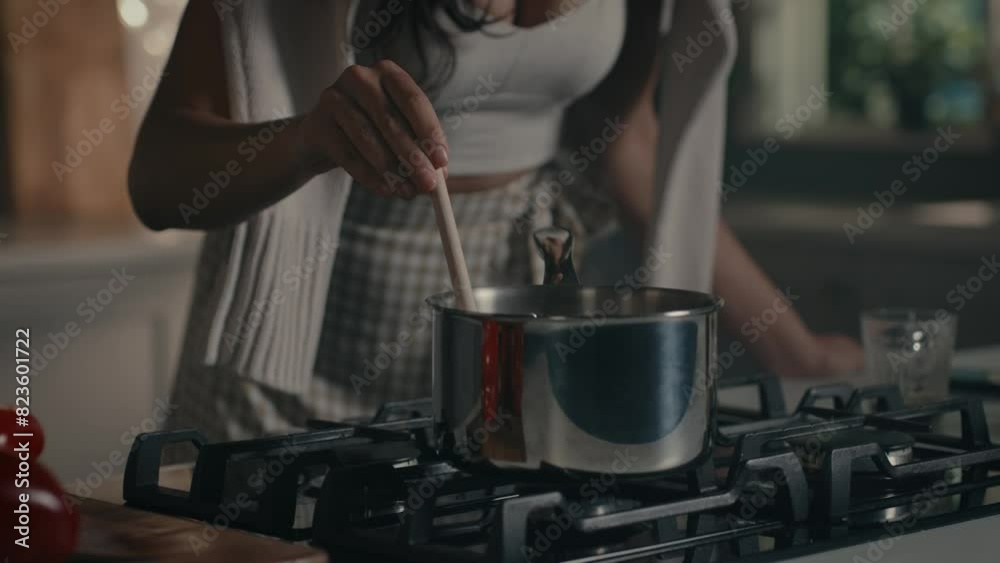 Pretty woman cooking soup on stove at kitchen. Close up of housewife preparing dinner at home. Young woman tasting soup on spoon at modern kitchen in slow motion, talking on phone, taking photos Pretty woman cooking soup on stove at kitchen. Close up of housewife preparing dinner at home. Young woman tasting soup on spoon at modern kitchen in slow motion, talking on phone, taking photos