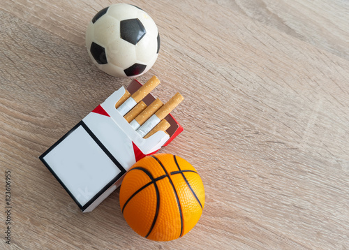 Smoking or sports. Sport ball and pack of cigarettes on table background. Top view