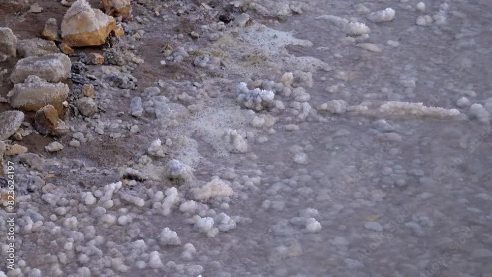 Close up of a natural salt formation in a salt lake, showcasing crystallized edible salt on rocks and water surface. Close up of a natural salt formation in a salt lake, showcasing crystallized edible salt on rocks and water surface.