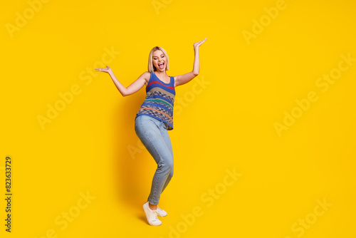 Photo portrait of young charming woman promoting her jeans and singlet dancing at dancehall nightclub isolated on yellow color background