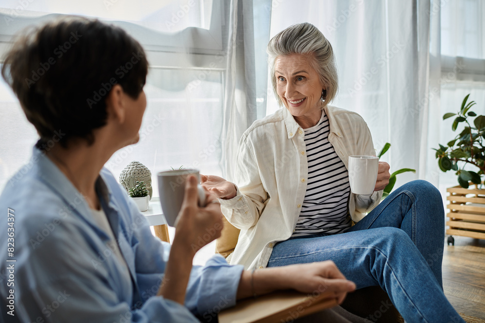 Two senior women enjoying a conversation on a sofa with coffee. Two senior women enjoying a conversation on a sofa with coffee.
