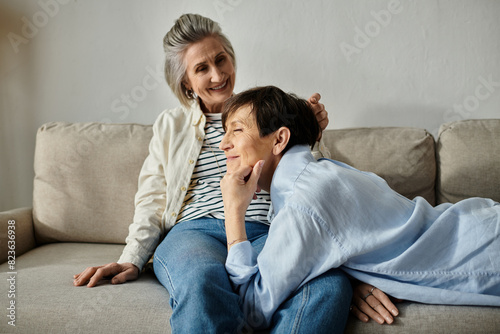 A mature lesbian couple relaxing together on a couch.