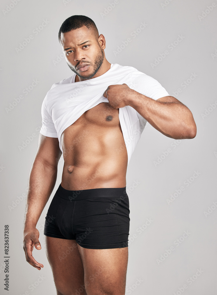 Portrait, abs and African man in tshirt in studio with confidence, pride and fitness in underwear on backdrop. Bodybuilder, athlete and body by white background with stomach, healthcare and workout