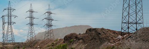 A wide panoramic view of an industrial landscape featuring power lines. Industrial impact on the environment. Mountains of rock and slag from iron ore.