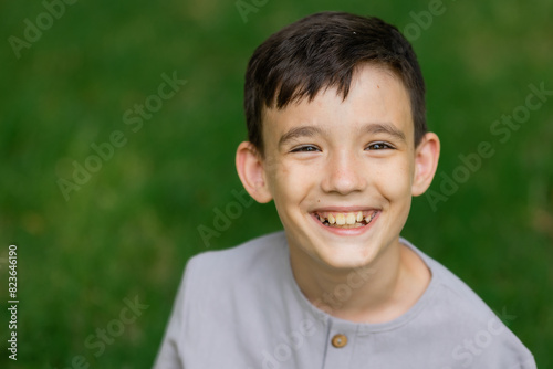 Portrait of a little boy on a green lawn laughing, looking at the camera,
