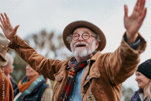 Senior man in hat and glasses raising his hands at the music festival. © Iigo