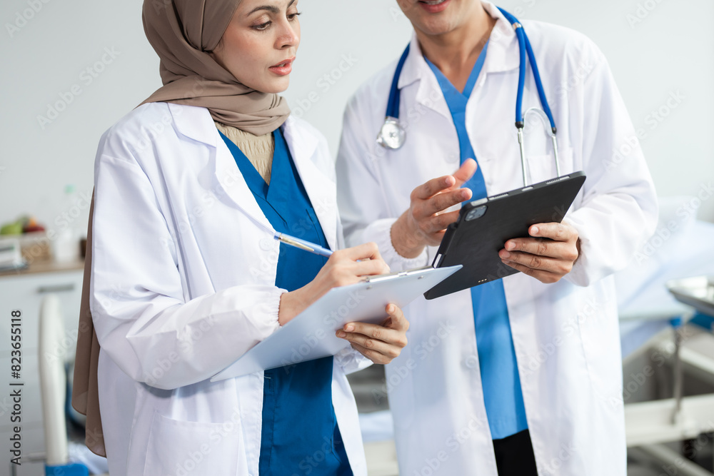 Hospital Ward. Doctor Talks With Professional Head Nurse or Surgeon, They Use Digital tablet Computer. Diverse Team of Health Care Hospital Ward. Doctor Talks With Professional Head Nurse or Surgeon, They Use Digital tablet Computer. Diverse Team of Health Care