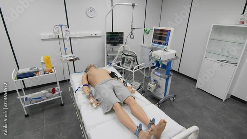 A medical mannequin is lying on a bed connected to the devices photo