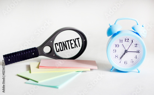 CONTEXT text on magnifying glass and white background with clock and stickers