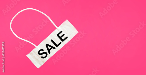 Light tag with the word Sale isolated on a pink background.