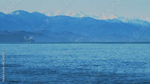 Fototapeta Naklejka Na Ścianę i Meble -  Wavy Black Sea Between Snowy Mountains. Sea By Snow Covered Mountains.