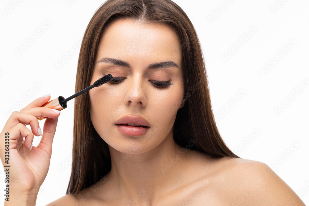 Young woman putting eye liner on eyelid on white background
