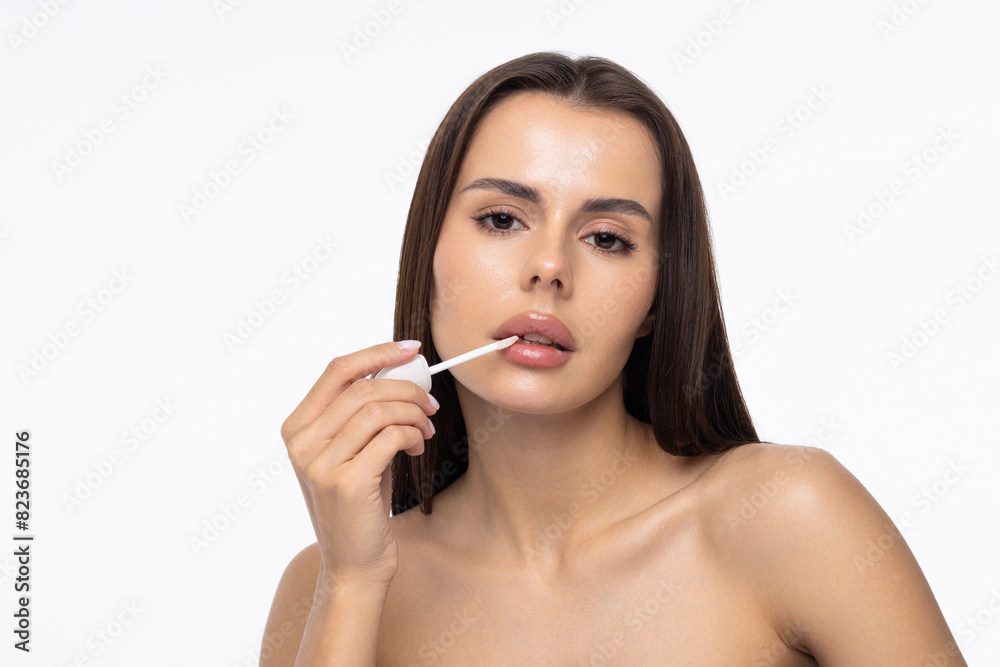 Young woman touching her lips with the finger and holding a hygienic lipstick in her hand on a white background. Young woman touching her lips with the finger and holding a hygienic lipstick in her hand on a white background.