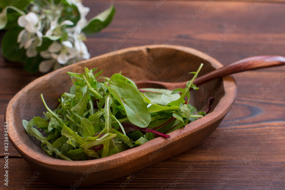 salad of arugula leaves and beetroot leaves in a wooden plate. Healthy eating salad of arugula leaves and beetroot leaves in a wooden plate. Healthy eating