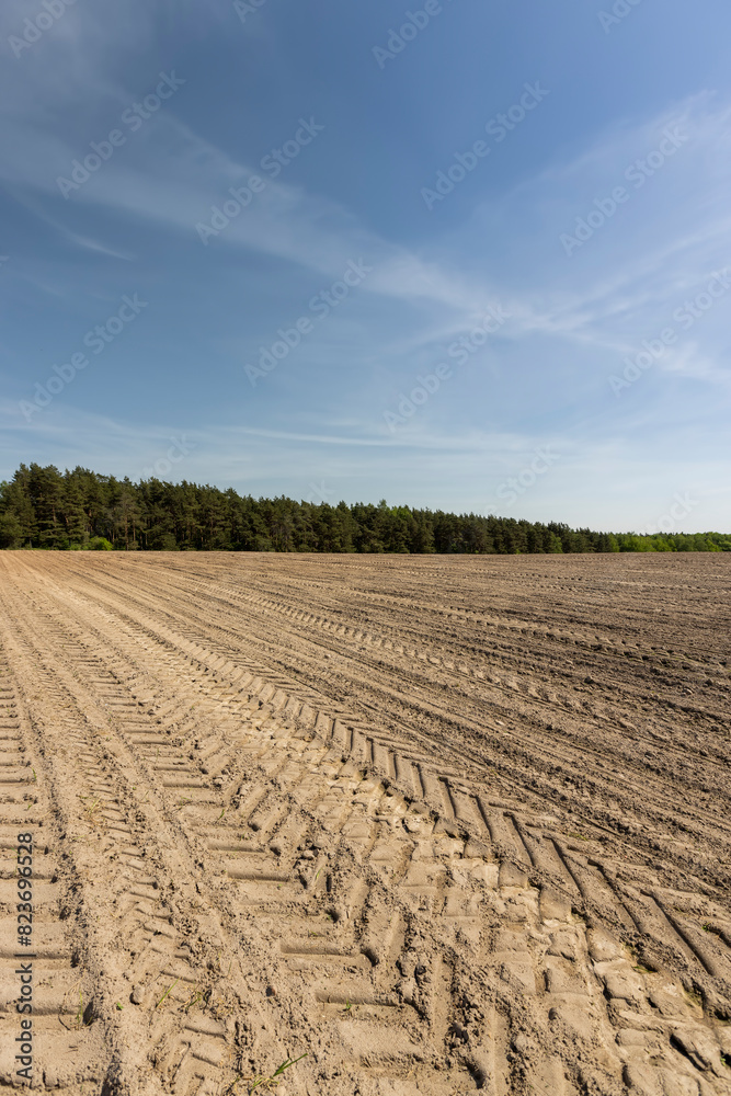plowed soil field with traces of cars and tractors plowed soil field with traces of cars and tractors