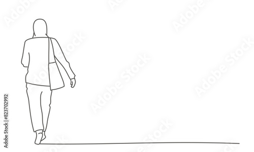 A woman is walking down a sidewalk with a handbag