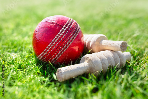 Cricket ball and bails on green grass of cricket pitch background photo