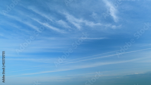 Clear blue sky with white wispy smoke clouds. Blue sky background with tiny stratus cirrus striped clouds. Timelapse. photo